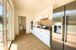 cocina con armarios blancos y nevera de acero inoxidable en 310 Lux Furnished flat, en Beaufort