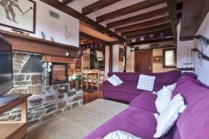 a living room with a purple couch and a fireplace at Apartamentos Tanau in Baqueira-Beret