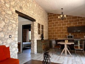 a living room with a table and a stone wall at Cabañas Rancho San Jorge in Bernal