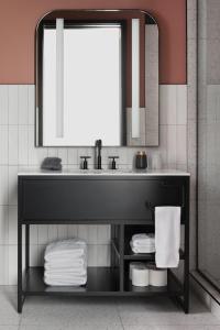 a bathroom with a sink and a mirror and towels at Kinn Guesthouse Downtown in Milwaukee