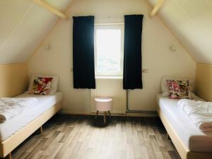 two beds in a room with a window at Vrij uitzicht Texel in De Koog +8 photos