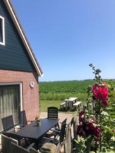 a patio with a table and chairs and flowers at Vrij uitzicht Texel in De Koog