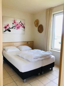 a bedroom with a white bed with flowers on the wall at Vrij uitzicht Texel in De Koog