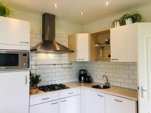 a kitchen with white cabinets and a stove top oven at Vrij uitzicht Texel in De Koog