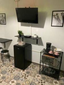 a room with a tv on a wall with a table at Hospederia Villa Alegre Estudio 7 in Cabo Rojo