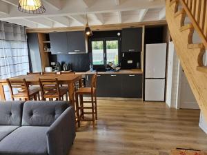 a kitchen and dining room with a table and a refrigerator at Maison bois de 65m² in Saint-Thibaud-de-Couz