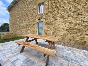 a wooden bench sitting in front of a brick building at Gîtes Marie Rose - PMR in Spincourt +7 photos