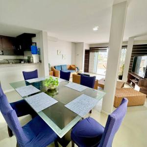 a dining room with a glass table and blue chairs at Departamento Familiar in Crucita