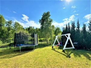 two swings in a field with trees in the background at Apartamenty Jeżynowa 20 in Rowy