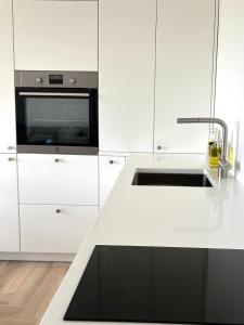 cocina blanca con fregadero y microondas en Liiva Paasukese Apartment en Liiva