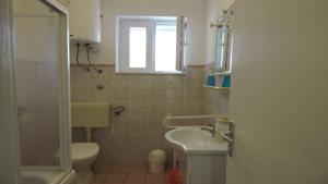 een badkamer met een wastafel, een toilet en een raam bij Apartments Ivanov in Novalja