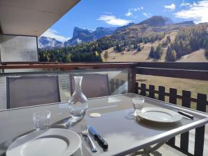 una mesa con dos platos y un jarrón en el balcón en Studio 4 Personnes côté Sud, en Superdevoluy