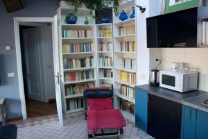 a kitchen with a red chair in front of a book shelf at Corte Cavour. Una mansarda nel cuore della città in Ravenna