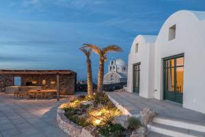 a villa with a patio with palm trees and a building at Patina Vivera Estate Santorini in Pyrgos