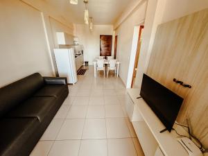 a living room with a black couch and a kitchen at Kitecabana Apartamento in Caucaia