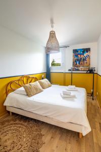 a bedroom with a large white bed with a yellow headboard at The Good Vibes Honfleur & pkg included in Honfleur