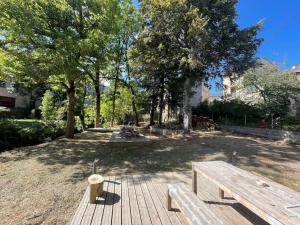 a park with two wooden benches and trees at Villa du Parc le Châtaignier in Formiguères
