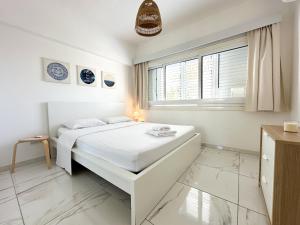 een witte slaapkamer met een bed en een raam bij Real Center in Larnaka