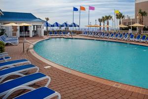 una piscina con sillas y sombrillas azules en SpringHill Suites by Marriott Virginia Beach Oceanfront, en Virginia Beach