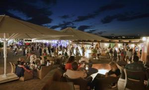 une foule de personnes assises sur des chaises dans un restaurant le soir dans l'établissement Mare e Montagna, à Villa San Pietro