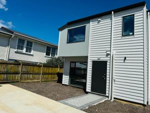 a white house with a black door and a fence at Holiday Home or Short term Rental in Papatoetoe in Auckland +4 photos