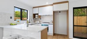 a kitchen with white cabinets and a white counter top at Holiday Home or Short term Rental in Papatoetoe in Auckland