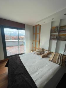 a bedroom with a large bed with a large window at EL ÁTICO DE LA PLAYA Parking gratis in Gijón