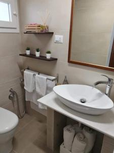 Un baño con lavabo, inodoro y espejo. en Il Bastione Apartment, en Gallipoli