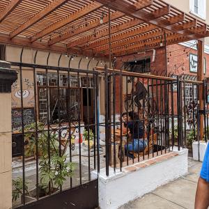 Una recinzione di metallo con un uomo seduto dentro di essa di Hospedaje Boutique Albergue Verde a Lima