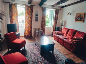 a living room with a red couch and two chairs at Maison Lafayette in Saint-Geniez-dʼOlt