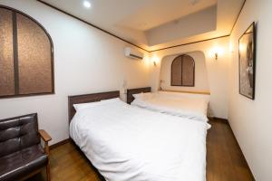 a bedroom with two beds and a leather chair at Grand Hotel Narita Airport - Vacation STAY 56520v in Narita
