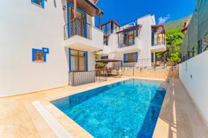 a villa with a swimming pool in front of a house at Pazar Apartments in Kalkan