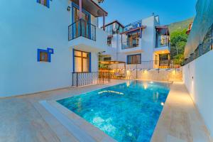 a villa with a swimming pool in front of a house at Pazar Apartments in Kalkan