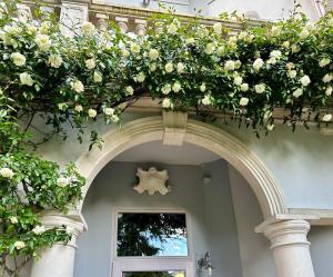 a building with an arch with white flowers on it at Historical Villa GINA with Magic Lake View in Dizzasco