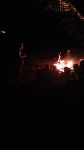 un grupo de personas de pie alrededor de un fuego por la noche en Lusis Homestay, en Lautoka