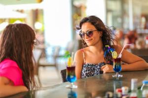 Dos mujeres sentadas en una mesa con un trago en Pine House by Werde Hotels, en Kemer