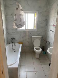 Harmony house apartments في Ker Bakary: حمام مع مرحاض وحوض استحمام ومغسلة