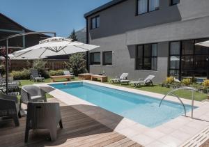a pool with chairs and an umbrella next to a building at Gluck Patagonia Aparts in Villa La Angostura