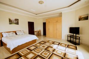 um quarto com uma cama e uma televisão de ecrã plano em ADRIEL HOMES WOODLAND CENTEr em Kigali
