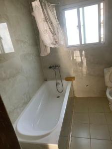 W łazience z oknem znajduje się biała wanna. w obiekcie Harmony house apartments w mieście Ker Bakary