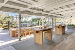 AC Hotel Gava Mar في غافا: فناء في الهواء الطلق مع طاولات وكراسي خشبية