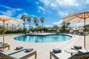 uma piscina com cadeiras e guarda-sóis num resort em AC Hotel Gava Mar em Gavà