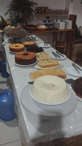 a table topped with cakes and cakes on plates at Pousada Ponta da Baleia in Barra Grande