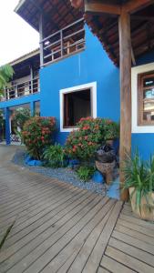 a blue house with flowers and plants in front of it at Pousada Ponta da Baleia in Barra Grande
