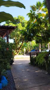 a wooden walkway with trees and a person walking in the distance at Pousada Ponta da Baleia in Barra Grande