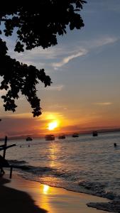 a sunset on the beach with boats in the water at Pousada Ponta da Baleia in Barra Grande