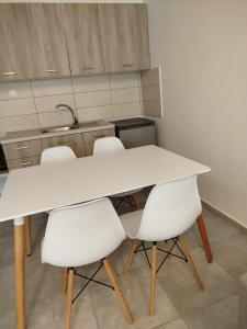 a kitchen with a white table and white chairs at Billy´s Seaside Apartment in Iraklitsa