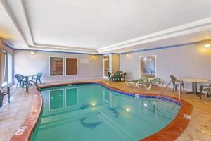 a swimming pool in a hotel with tables and chairs at Comfort Inn & Suites Chesapeake - Portsmouth in Chesapeake