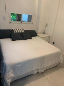 Una cama blanca con almohadas negras en un dormitorio en Eugene City en Buenos Aires
