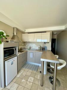 une cuisine avec des placards blancs et une table. dans l'établissement Superbe appartement en bord de mer, près du centre et des plages, à Menton